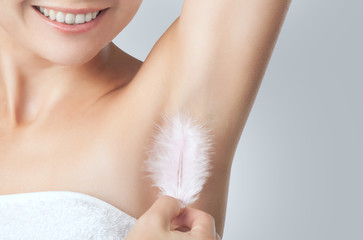 After the botulinum toxin injection procedure. A woman holds a feather in the skin in the armpits,...