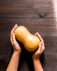 Dynia trzymana w rękach na ciemnym, klimatycznym, drewnianym tle  © Nicole