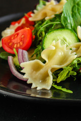 italian pasta salad farfalle, vegetables, mix leaves (tomato, cucumber, onion, lettuce, chard, arugula and more) menu concept. food background. copy space. Top view
