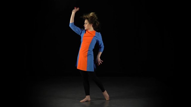 Girl in bright dress, unusual makeup and crazy hairstyle makes hand gestures
