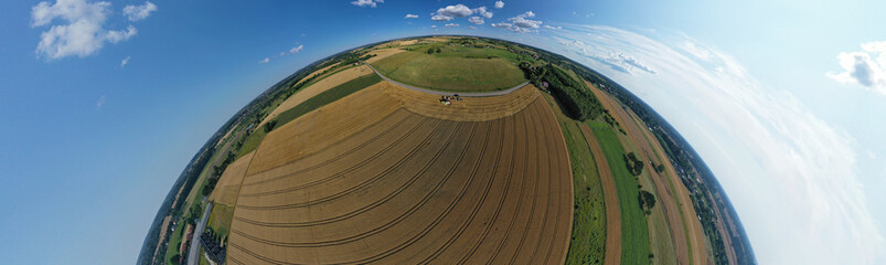Aerial drone 180 degree arch view on harvester unloading seed to tractor trailer, agricultural landscape