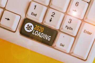 Word writing text 2020 Loading. Business photo showcasing Advertising the upcoming year Forecasting the future event White pc keyboard with empty note paper above white background key copy space