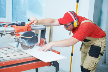 Tiler cutting tile on wet saw machine