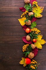 Liście, orzechy, jarzębina i dary jesieni na drewnianym tle, miejsce na napis 