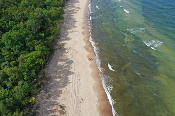 Aerial drone perspective view on beautiful and silent paradise place with forest, clean sand beach and turquoise sea waves. People walking
