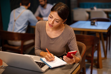 Young woman working overtime with laptop in cafe