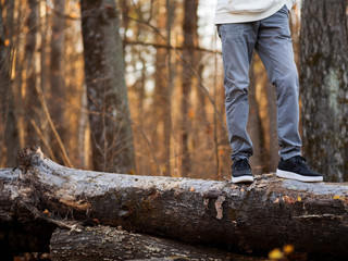 Men's feet in stylish black sneakers in autumn Park or forest. Seasonal shoes. Copy space