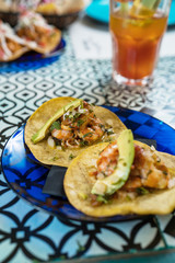 Real Mexican Tacos on a plate. Real Mexican Tacos on a plate. Shrimp tacos with homemade salsa, limes and parsley on wooden board over dark background. Top view. Mexican cuisine