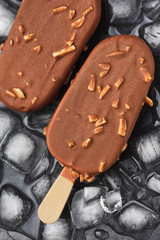 Chocolate ice cream popsicle on black background with ice