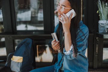 Happy Asian lady in glasses holding smartphone