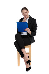 businesswoman sitting and reading something on clipboard intrigued