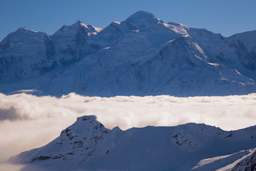 Obraz premium Panorama of mountains rising from the clouds