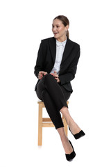 businesswoman sitting with crossed legs and looking aside excited