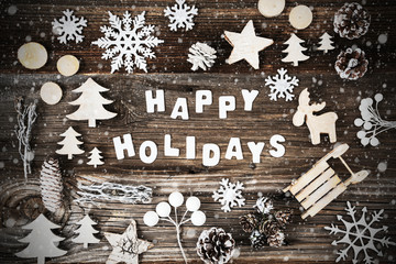 White Letters Building The Word Happy Holidays. Wooden Christmas Decoration Like Tree, Sled. Brown Wooden Background With Snowing Snowflakes