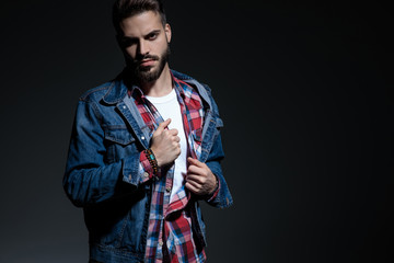 Motivated casual man adjusting his shirt and looking
