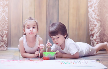 Little children paint on a large sheet of paper