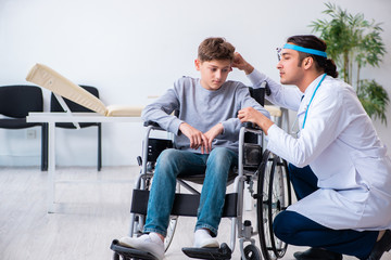 Fototapeta premium Young male doctor pediatrist and boy in wheel-chair