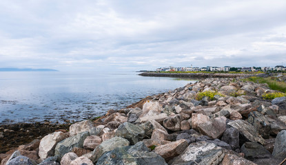 View of Salthill village & beach on a beautiful summer day, with rocks in the foreground. Near Galway Ireland