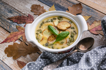 Autumn cream soup with vegetables, croutons, pumpkin seeds and fresh spinach on a rustic background. Top view