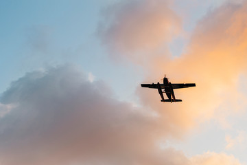 flying biplane (old airplane) at sunset time and behind the clouds