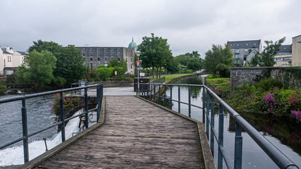 City center Galway and the River Corrib with old buildings, bridges, fauna and cloudy sky. Taken in sumer.