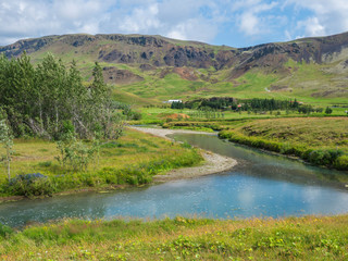 Naklejka na ściany i meble Idyllic landscape of Hveragerdi near Reykjadalur valley with hot springs river, lush green grass meadow and hills. South Iceland. Summer sunny morning, blue sky.