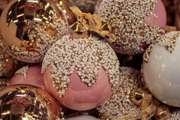 Bright and shining Christmas balls in pink, white and gold, decorated with gold and beads with a...