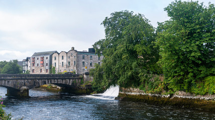 City center Galway and the River Corrib with old buildings, bridges, fauna and cloudy sky. Taken in sumer.