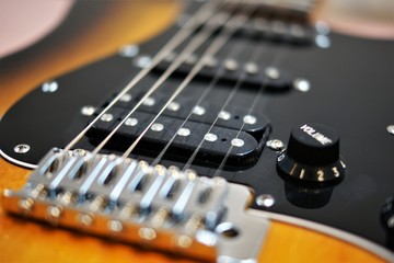 Fototapeta na wymiar chrome colored bridge and black pickups of an e-guitar closeup