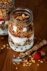 Healthy diet breakfast with granola, yogurt, fruits, berries glass jars on wooden background.
