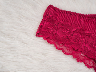 Lace of raspberry panties on white fur. Close up. Fashionable concept of lingerie