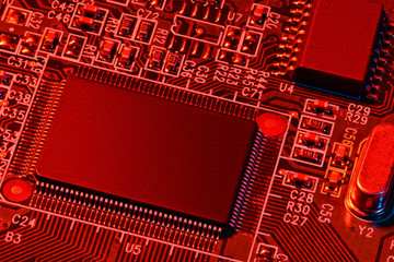 printed circuit board and microchip, or cpu, in red light closeup - electronic component for digital equipment, concept for development of electric computer circuits