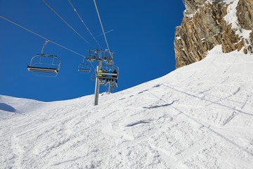 Fototapeta na wymiar Ski lift on the Alps close to mountain cliffs