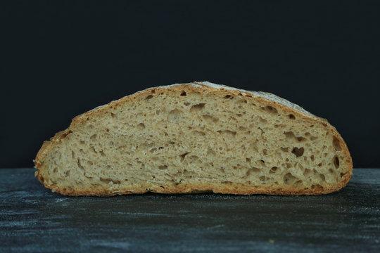 Fresh homemade round bread on a dark background. Mother dough bread. Homemade bread sourdough, rustic baked bread. minimalism