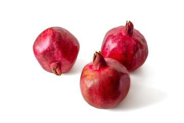 Three dark red pomegranates on a white background