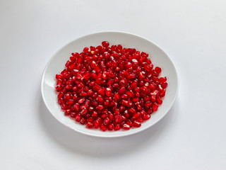 White plate with peeled red pomegranate seeds
