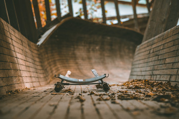 Abandoned luge track in pine woods. Wooden bobsleigh track curves along the trees with vintage luge sled on the track covered in leaves. Outdated sport complex in Murjani, Latvia. 