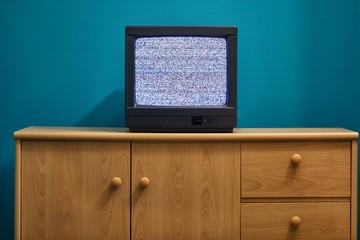 Old TV set with blank white screen in a dim room