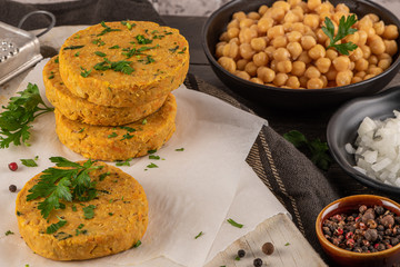 Raw veggie burger with chickpeas, vegetables and parsley leaves on kitchen countertop
