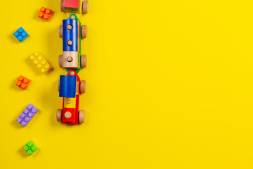 Toy background. Wooden toy train and colorful building brick blocks on yellow background