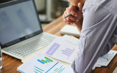 Side view of experienced businessman looking at financial data with graphics and charts while work...