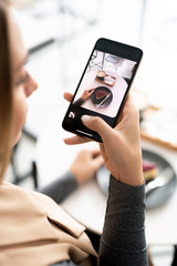 Female millennial with smartphone taking photo of dessert and drink in cafe