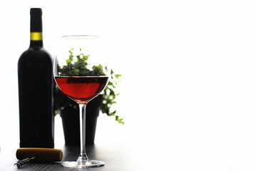 A glass of red dry wine on the table. Dark bottle and glass of wine.