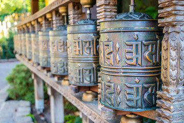 Fototapeta na wymiar Buddhist prayer wheels, cylindrical rolls on a spindle made from metal and wood, selective focus