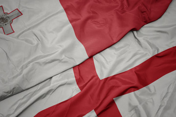 waving colorful flag of england and national flag of malta.