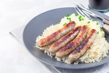 Roasted nuremberg sausages served with sour cabbage and mashed potatoes, on  gray plate, horizontal, copy space