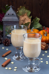 Hot white chocolate with pumpkin and spices, autumn decorations on background, vertical