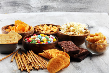 Salty snacks. Pretzels, chips, crackers in wooden bowls and candy and chocolate on table