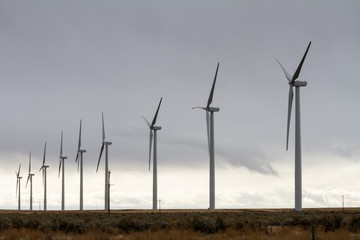 wind turbines making electricity against a cloud sky