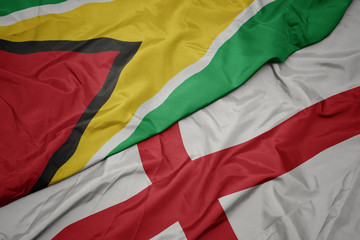 waving colorful flag of england and national flag of guyana.